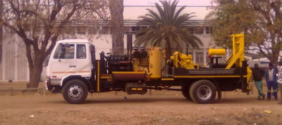 Yellow and white drilling rig parked on site