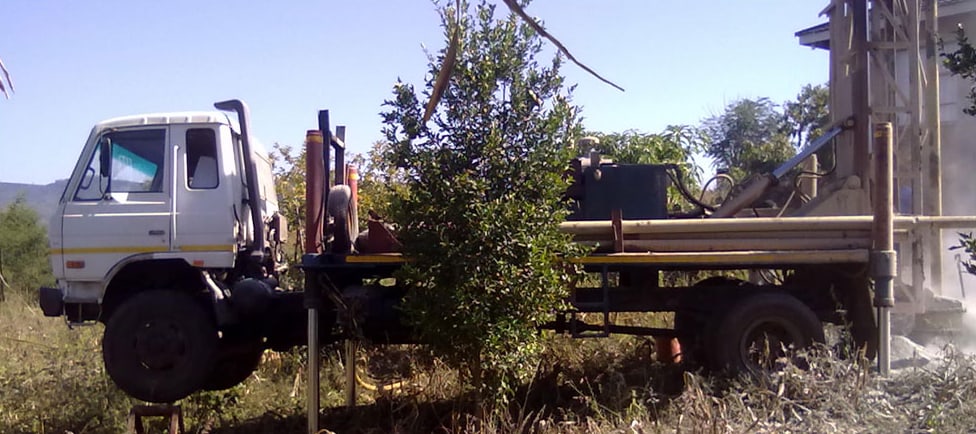 Drilling rig working between trees on a smallholding